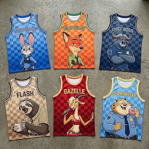 Puede incluir: Seis camisetas de baloncesto coloridas con personajes de una pel&iacute;cula de dibujos animados. Las camisetas tienen los nombres "Judy Hopps", "Nick Wilde", "Chief Bogo", "Flash", "Gazelle" y "Clawhauser" impresos. Cada camiseta tiene una ilustraci&oacute;n de personaje diferente y un fondo a cuadros.
