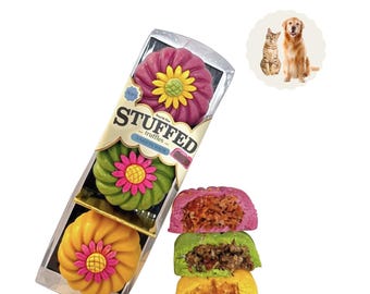May include: A clear plastic package containing three flower-shaped treats in magenta, green, and yellow, labeled STUFFED truffles VARIETY PACK. Beside the package are three halved treats showing textured fillings, with a small circular inset of a cat and dog.