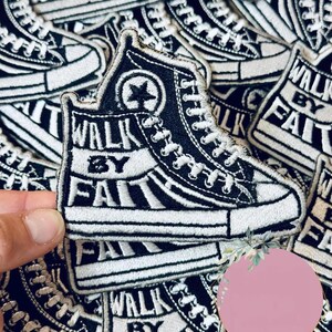 May include: Black and white embroidered patch featuring a high-top sneaker design. The patch includes the text "WALK BY FAITH" and a star emblem. The patches are stacked together.