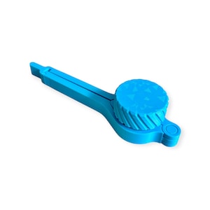 Könnte beinhalten: Ein leuchtend blauer Dosenöffner aus Kunststoff mit einer strukturierten, kreisförmigen Oberseite und einem Griff. Der Dosenöffner hat ein Hebeldesign und ein kleines, rechteckiges Ende. Die kreisförmige Oberseite hat ein Dreiecksmuster.