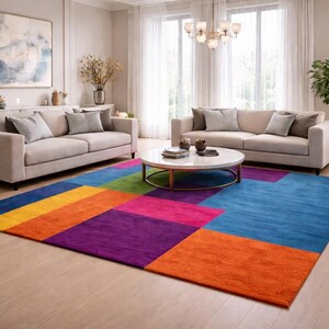 May include: A modern living room featuring two beige sofas, a round coffee table, and a colorful geometric rug. The rug has blocks of blue, orange, purple, pink, and green. The room is well-lit with natural light.