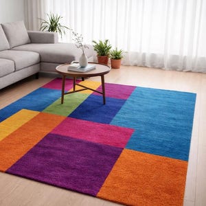 May include: A colorful geometric area rug with a modern design. The rug features large blocks of color in shades of blue, orange, yellow, green, pink, and purple. A gray sofa and a wooden coffee table are in the background.