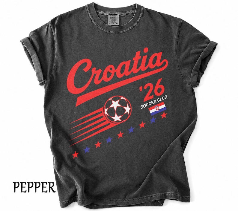 May include: A charcoal gray t-shirt featuring the red text Croatia above a graphic of a soccer ball with motion lines. The design includes the text '26 SOCCER CLUB, a small Croatian flag, and a row of alternating red and blue stars across the chest.