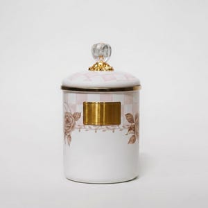 Peut inclure: Un pot en céramique blanc avec un couvercle à motif à carreaux roses et blancs. Le pot a un bord doré et une plaque rectangulaire dorée. Il est décoré d'illustrations de roses et d'un bouton en cristal.
