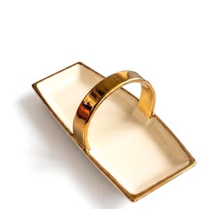 Plato rectangular de gres para servir, con borde dorado y asa en relieve, ideal como centro de mesa.