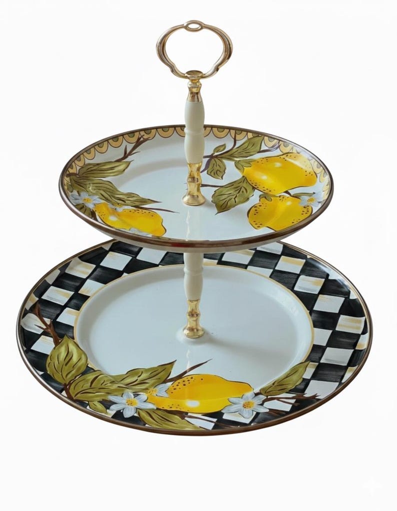 Puede incluir: Bandeja de servir de dos niveles con asa dorada y soporte color crema. El nivel superior presenta un dise&ntilde;o de lim&oacute;n y hojas, mientras que el nivel inferior tiene un borde a cuadros en blanco y negro con un dise&ntilde;o de lim&oacute;n y flores.