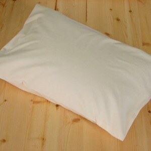 May include: A rectangular, off-white pillowcase rests on a light-colored wooden surface. The pillowcase is made of a soft, smooth fabric and appears to be empty. The pillowcase is a neutral color, suitable for various bedroom decor styles.