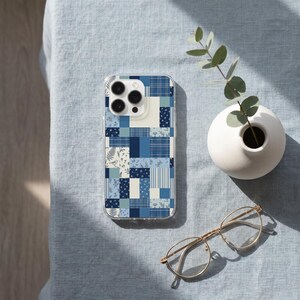 May include: A clear smartphone case featuring a blue and white patchwork design with various patterns including stripes, plaids, and floral motifs with small birds. The case has a cutout for a triple-lens camera system on the upper left corner.