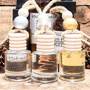 May include: Three glass bottles with droppers and wooden stoppers. The bottles are filled with clear liquid and have a rustic, natural look. The bottles are labeled with the text "Ace" and "Hill Mist".