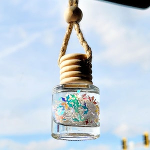 May include: A clear glass bottle with a wooden top and a string hanging from it. The bottle is filled with colorful confetti.