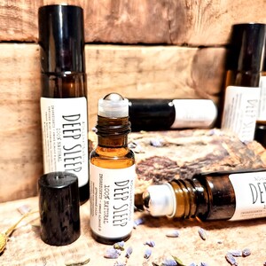 May include: Four brown glass roller bottles with black caps and silver roller balls. The bottles are labeled "Deep Sleep 100% Natural" and list ingredients including sweet almond and grapeseed oil.