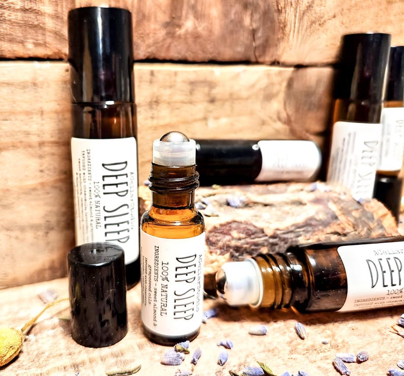 May include: Four brown glass roller bottles with black caps and silver roller balls. The bottles are labeled "Deep Sleep 100% Natural" and list ingredients including sweet almond and grapeseed oil.