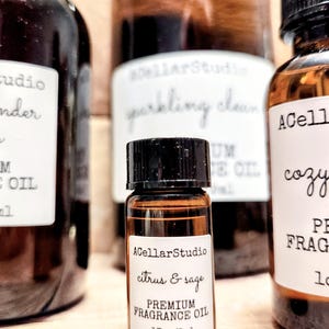 May include: A small brown glass bottle with a black cap and a white label that reads "ACellarStudio citrus & sage PREMIUM FRAGRANCE OIL .17oz/5ml".