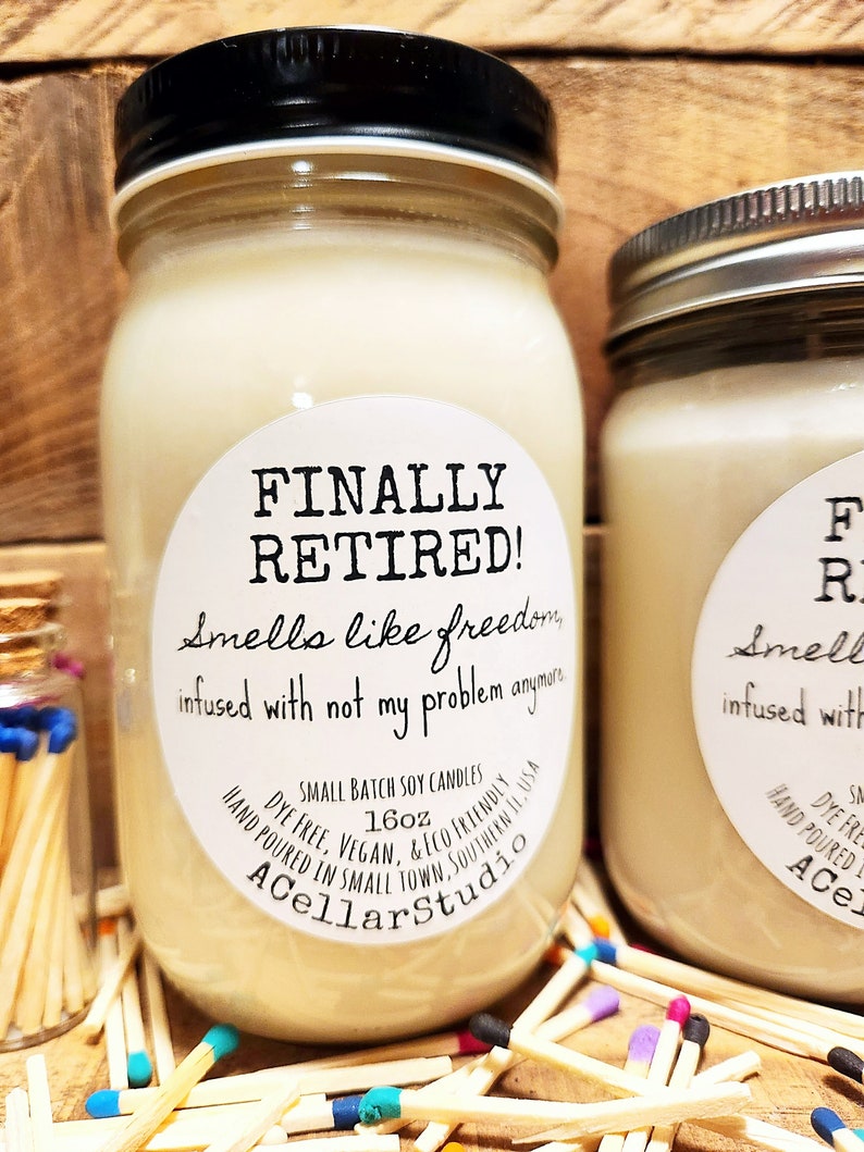 K&ouml;nnte beinhalten: Eine wei&szlig;e Sojawachskerze in einem Glasgef&auml;&szlig; mit schwarzem Deckel. Das Etikett lautet "FINALLY RETIRED! Smells like freedom infused with not my problem anymore" und "SMALL BATCH SOY CANDLES 16oz DYE FREE. VEGAN. & ECO FRIENDLY HAND POURED IN SMALL TOWN. SOUTHERN IL USA ACellarStudio".