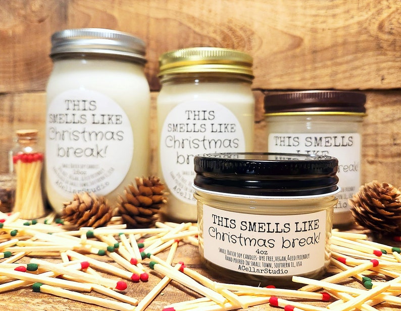 以下が含まれることがあります： 「This smells like Christmas break!」と書かれたラベルが付いたキャンドルが4本あります。キャンドルはさまざまなサイズで、マッチで囲まれています。最も小さいキャンドルは4オンスのキャンドルです。