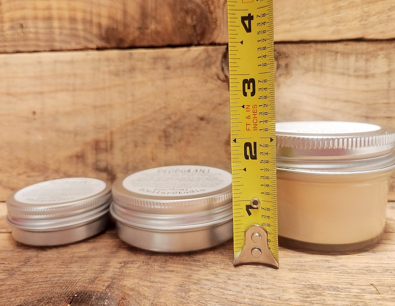 May include: Three different sized metal tins with lids. The largest tin is 2.5 inches tall and contains a light beige cream. The smaller tins are empty.
