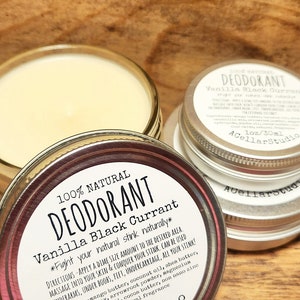 Puede incluir: Dos latas plateadas de desodorante natural con una etiqueta blanca que dice "100% Natural Desodorante Vainilla Grosella Negra *Combate tu olor natural de forma natural*" e instrucciones de uso. La etiqueta tambi&eacute;n incluye el texto "1 oz/30ml AcellarStudio".