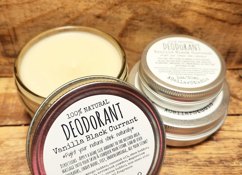 Puede incluir: Dos latas plateadas de desodorante natural con una etiqueta blanca que dice "100% Natural Desodorante Vainilla Grosella Negra *Combate tu olor natural de forma natural*" e instrucciones de uso. La etiqueta tambi&eacute;n incluye el texto "1 oz/30ml AcellarStudio".
