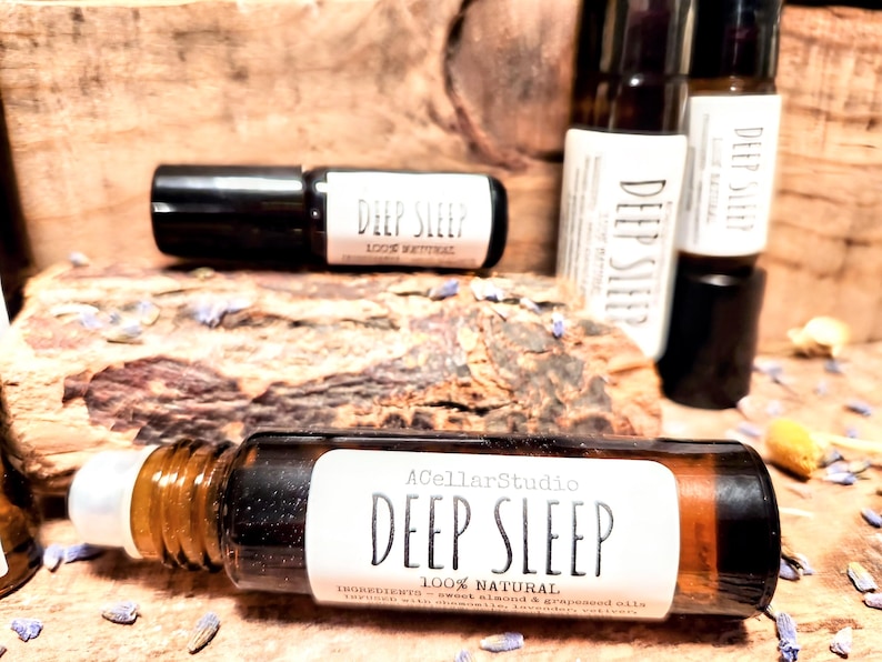 May include: A brown glass roller bottle with a white label that reads "A Cellar Studio Deep Sleep 100% Natural Ingredients: Sweet Almond &  Grapeseed Oil".
