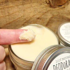 Puede incluir: Primer plano de un dedo que se introduce en un tarro de desodorante natural. El tarro est&aacute; etiquetado con "100% NATURAL DESODORANTE Grosella Negra".