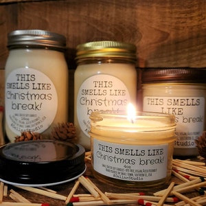 以下が含まれることがあります： ソイワックスキャンドルが入ったガラス瓶が3つ。瓶には「This smells like Christmas break!」とラベルが貼られており、木製のマッチで囲まれています。キャンドルはサイズが異なり、一番大きい瓶は160g、一番小さい瓶は4ozです。