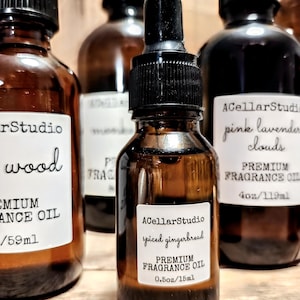 May include: Three amber glass bottles with black lids and labels. The center bottle is a smaller size and contains a premium fragrance oil with a spiced gingerbread scent. The label reads "ACellarStudio spiced gingerbread PREMIUM FRAGRANCE OIL 0.5oz/15ml".