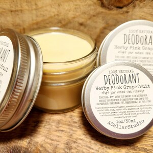 May include: A silver jar with a clear glass lid filled with a yellow-colored natural deodorant. The jar has a label that reads "100% Natural Deodorant Herby Pink Grapefruit *Fight your natural stink naturally*" with a list of ingredients and directions for use. The label also includes the brand name "A Cellar Studio" and the size "1 oz/30 ml".