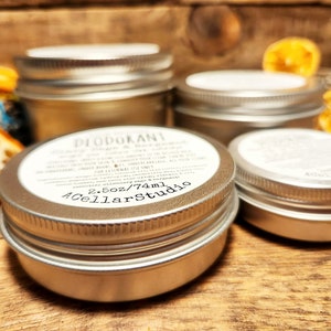May include: Four silver metal containers with lids. The container in the foreground has a white label that reads "DEODORANT" and "2.5oz/74ml" and "A Cellar Studio".