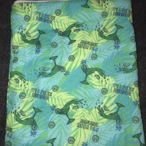May include: A fabric with a tropical theme, featuring a pattern of green margarita glasses, lime slices, and palm leaves on a blue and green background. The text "IT'S 5 O'CLOCK SOMEWHERE" is repeated throughout the design.