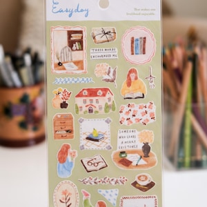 Può includere: Un foglio di adesivi decorativi con varie illustrazioni ad acquerello. Gli adesivi presentano immagini di libri, case, fiori e persone. Il testo include "Easyday" e "These words encouraged me."