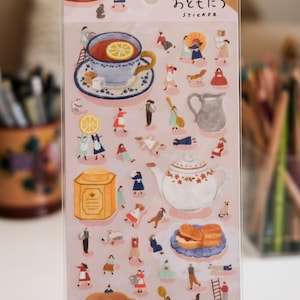 May include: A sticker sheet with illustrations of tea party elements. The stickers depict teacups, a teapot, biscuits, and small figures. The text "ひみつの おともだち STICKER" is printed at the top.