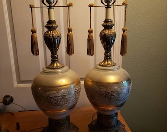 May include: A pair of vintage table lamps with white and gold glass bases, gold accents, and gold tassel accents.