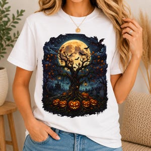 May include: A white short-sleeve t-shirt featuring a graphic print of a dark, gnarled tree under a large full moon. The scene includes hanging lanterns, flying bats, a distant castle, a graveyard, and several glowing jack-o'-lanterns at the base.