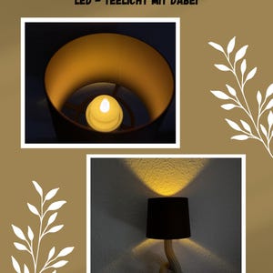 May include: An LED tealight candle inside a black lampshade, with the text "1X KOSTENLOSES LED - TEELICHT MIT DABEI" at the top. The lamp is on a beige wall, with a decorative branch on the right.