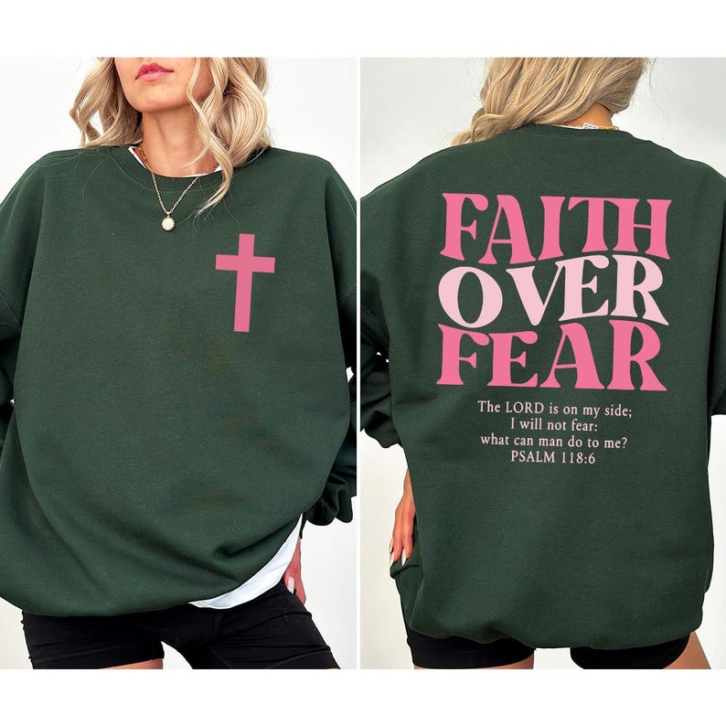 May include: Dark green sweatshirt with a pink cross on the front. The back of the sweatshirt features the text "FAITH OVER FEAR" in pink, along with the Bible verse Psalm 118:6. A comfortable, casual top for everyday wear.