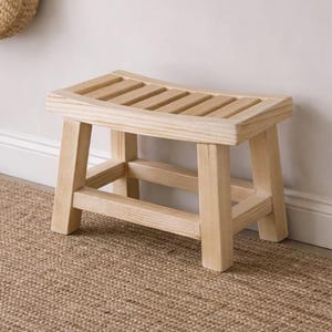 May include: A neutral-toned entryway with a woven jute rug, a small wooden bench, and a wall-mounted shelf. A round mirror hangs above the shelf, and a vase with dried pampas grass sits on the shelf. A woven basket holds an umbrella.