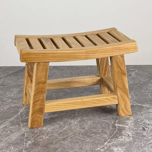 Könnte beinhalten: Ein kleiner Holzhocker mit einer geschwungenen, gelatteten Sitzfläche und vier stabilen Beinen, die durch horizontale Stützstangen verbunden sind. Die natürliche hellbraune Holzmaserung ist auf der gesamten rechteckigen Struktur sichtbar.