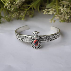 May include: A white ceramic mug with a black handle and the text "But First, Coffee" in a bold, black font. The mug is set against a blurred background, suggesting a cozy setting.