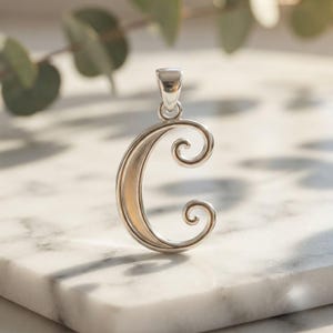 May include: A silver-toned metal pendant shaped like the letter C, featuring a smooth, curved design with decorative swirls at the top and bottom terminals. The pendant includes a small, integrated bail at the top for attachment to a chain.