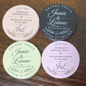 May include: Four circular drink tokens in light pink, black, light green, and lavender. The tokens feature printed text including "Jamie & Leanne," "Drinks Token," "Redeem at the bar," "Thankyou for celebrating with us," and the date 24-09-2026.