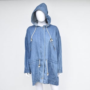 May include: A light blue denim jacket with a hood and a drawstring waist. The jacket has a zipper closure and two pockets on the front.
