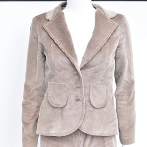 May include: A tan corduroy blazer with a notched lapel, two front pockets, and two buttons. The blazer is part of a suit and is displayed on a mannequin against a white background.