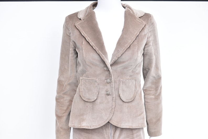 May include: A tan corduroy blazer with a notched lapel, two front pockets, and two buttons. The blazer is part of a suit and is displayed on a mannequin against a white background.