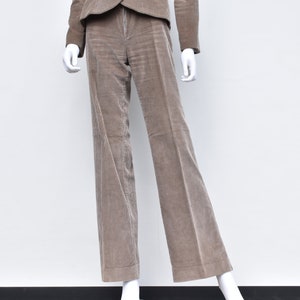 May include: A taupe corduroy suit on a mannequin. The suit comprises a blazer and wide-leg trousers. The fabric has a vertical ribbed texture. The mannequin is set against a plain white background.
