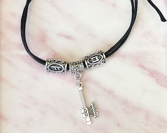 May include: A black cord bracelet with three silver beads and a silver axe charm. The beads have intricate designs.