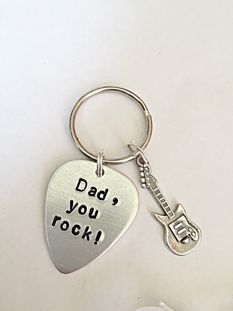 May include: Silver guitar pick keychain with the text "Dad, you rock!" and a small silver guitar charm.