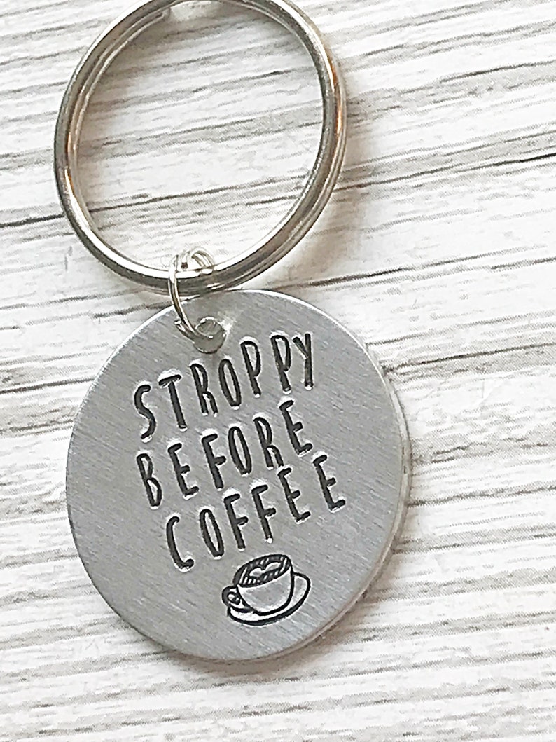 May include: Silver keychain with a round tag that says "STROPPY BEFORE COFFEE" with a small coffee cup icon.