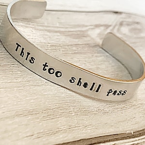 Könnte beinhalten: Silberarmband mit der Gravur "This too shall pass".