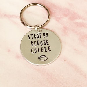 May include: Silver keychain with the text "STROPPY BEFORE COFFEE" and a small coffee cup icon.