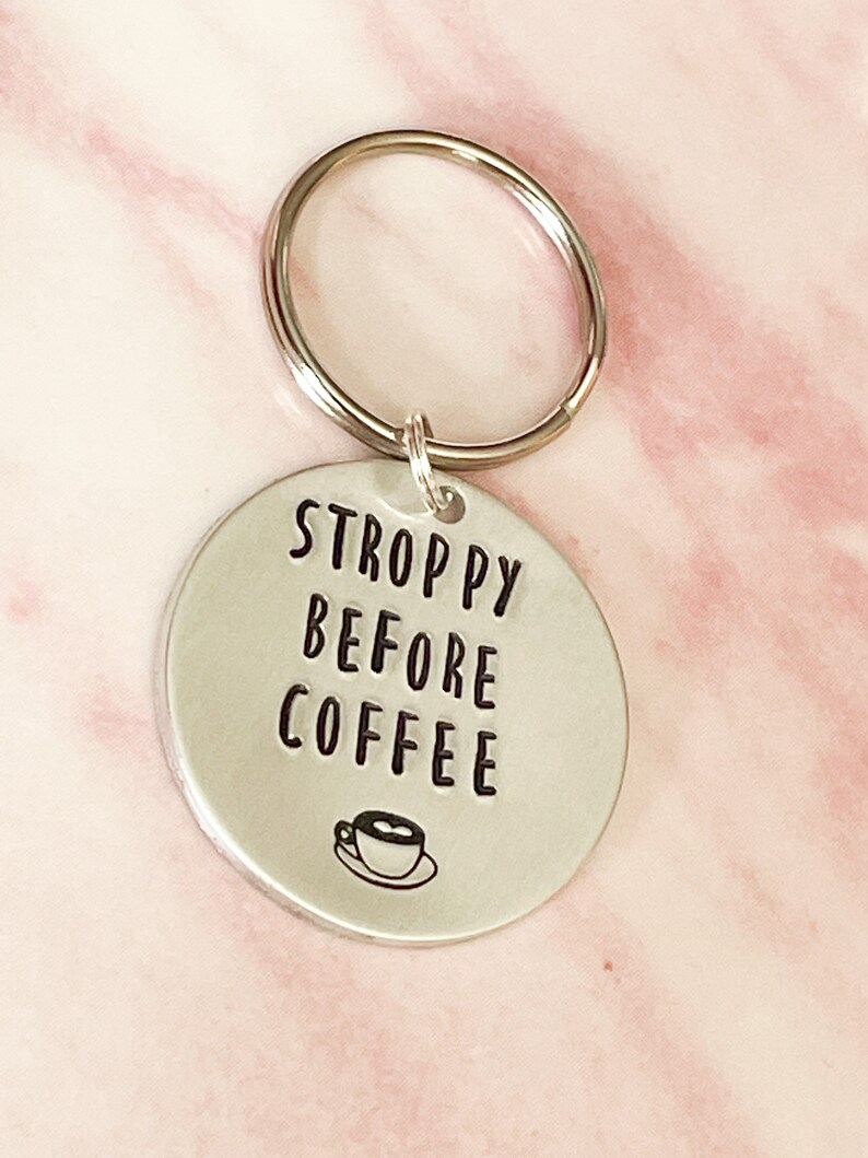 May include: Silver keychain with a round tag that says "STROPPY BEFORE COFFEE" with a small coffee cup icon.